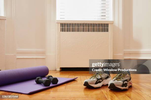 yoga mat, weights and sports shoes on floor at home gym - exercise room stock-fotos und bilder