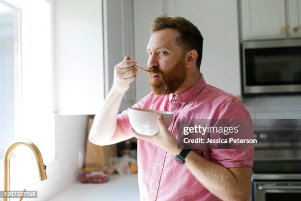 man eating cereal breakfast in kitchen - frühstücksflocken stock-fotos und bilder