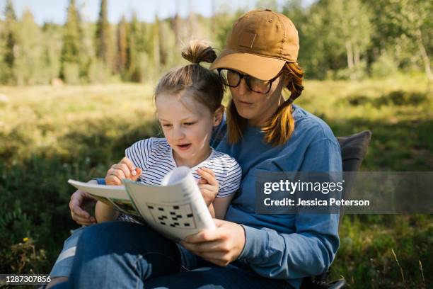 usa, utah, uinta national park, mother and daughter (6-7) doing crossword in meadow in forest - crossword puzzle stock pictures, royalty-free photos & images