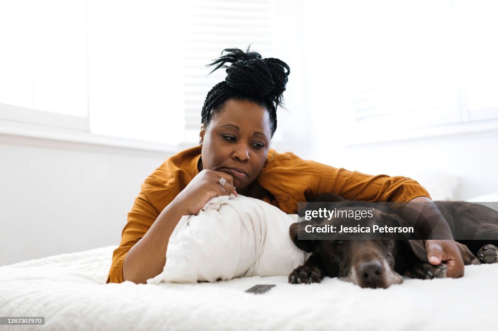 Sad woman lying on bed with dog
