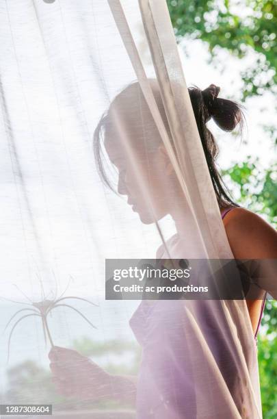 profile of woman holding plant behind curtain in tropical landscape - puket fotografías e imágenes de stock