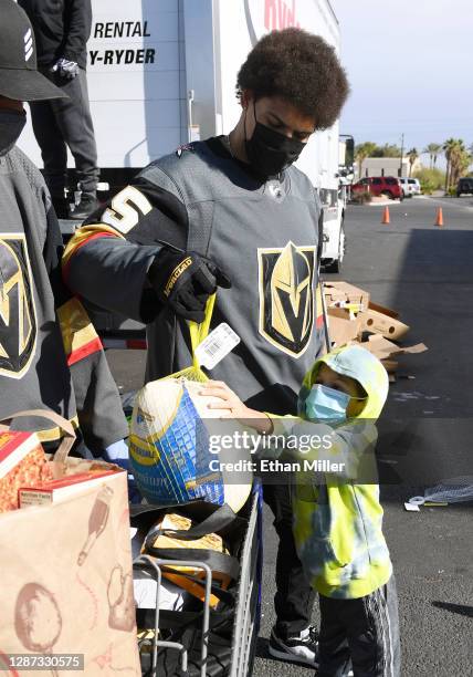 Ryan Reaves of the Vegas Golden Knights and his 4-year-old son Kanen Reaves put a turkey in a grocery cart at the HELP of Southern Nevada campus on...