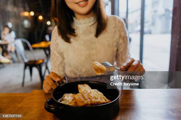 jonge aziatische vrouw die van fish and chipsmaaltijd in een café geniet - fish chips stockfoto's en -beelden