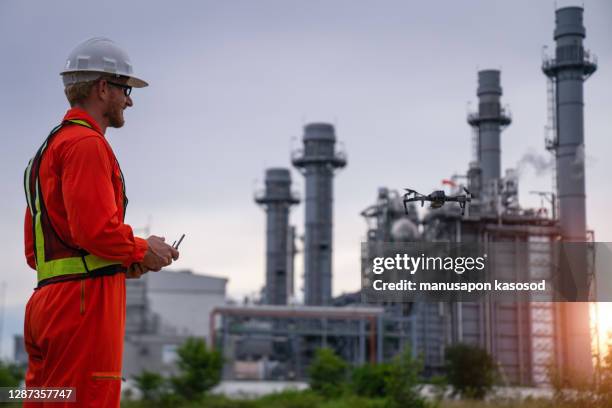 engineer piloting drone at building site - gas works stock pictures, royalty-free photos & images