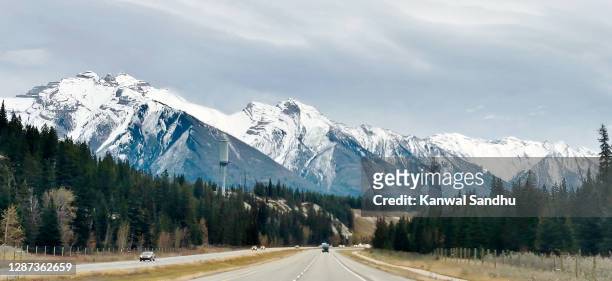 empty trans canada highway with snow covered mountains along the way - autostrada transcanadese foto e immagini stock