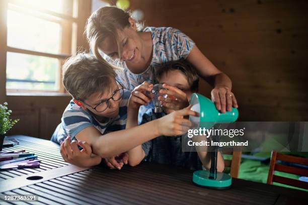 mother and kids saving energy by changing bulbs - sustainable lifestyle family stock pictures, royalty-free photos & images