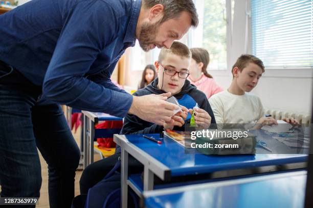 leraar speciaal onderwijs in nauwe samenwerking met een van zijn leerlingen - special needs stockfoto's en -beelden