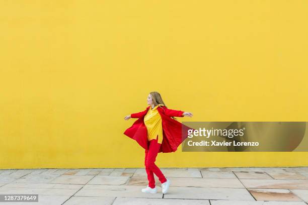 woman dancing in front of a yellow wall - person standing infront of wall stockfoto's en -beelden