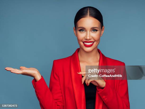 beautiful emotional woman presenting your product - red jacket stock pictures, royalty-free photos & images
