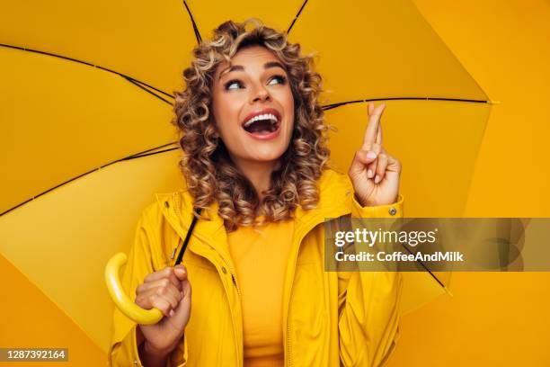 girl with yellow umbrella - fingers crossed stock pictures, royalty-free photos & images