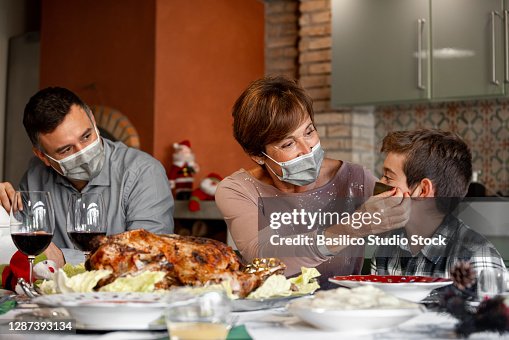 Grandmother adjust the surgical mask to her grandson during Christmas dinner. Grandmother adjust the surgical mask to her grandson during Christmas dinner.
