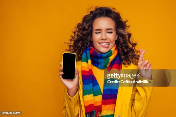 mooi meisje met slimme telefoon die haar vingers kruist en voor goed geluk wenst - scarf isolated stockfoto's en -beelden