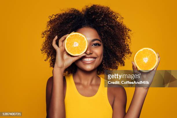 schöne afro-mädchen mit einem orange - vitamin c stock-fotos und bilder