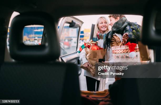 couple in love having fun while packing christmas presents in a car trunk - xmas car stock pictures, royalty-free photos & images