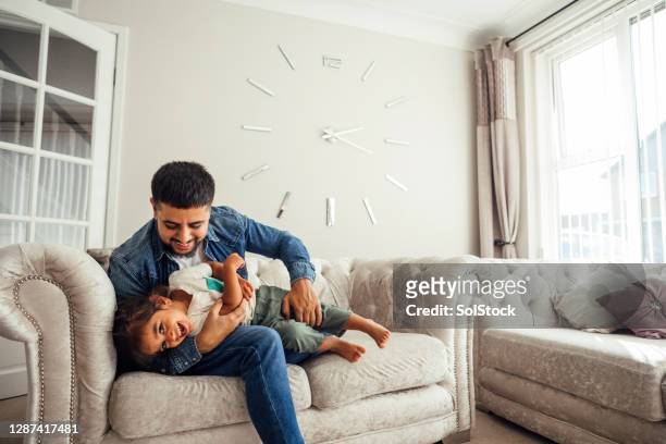 父親和兒子在客廳的沙發上玩耍 - 玩耍式打鬧 個照片及圖片檔