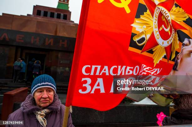Une femme russe nostalgique du régime communiste se recueille avec un drapeau de l'Union Soviétique devant le mausolée de Lénine sur la Place Rouge...