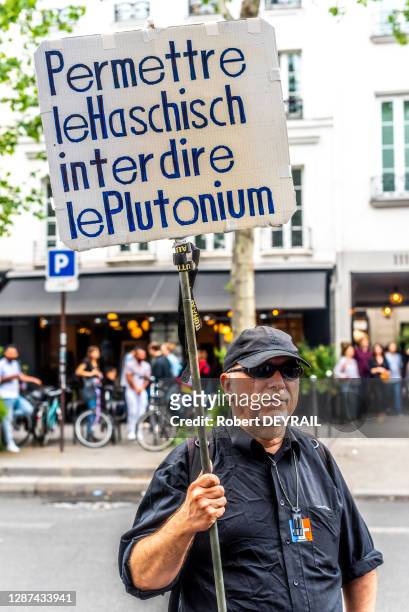 Une personne agée brandie une pancarte portant l'inscription "Permettre le hashisch, interdire le plutonium" lors de la Cannaparade pour la...