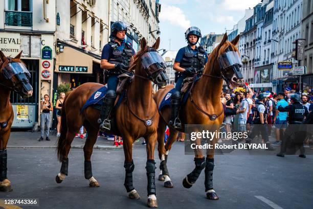 Policiers à cheval et supporters de l'équipe de France de football lors de la finale de la coupe du monde le 15 juillet 2018, Paris, France.