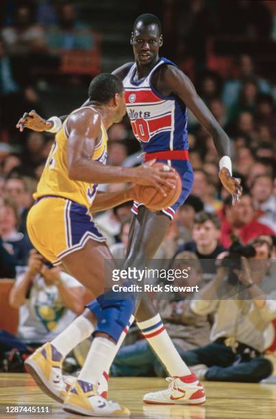 Manute Bol, Center for the Washington Bullets challenges Magic Johnson of the Los Angeles Lakers during their NBA Pacific Division basketball game on...