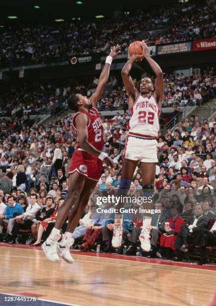 John Salley, Power Forward for the Detroit Pistons attempts a three point shot as Ron Anderson, Small Forward for the Philadelphia 76ers reaches to...