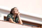 Happy woman breathing fresh air from balcony in apartment