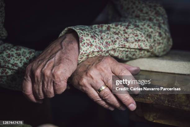 selective focus on the hands of an older man with a ring resting on a wooden table - hand resting on wood stock-fotos und bilder