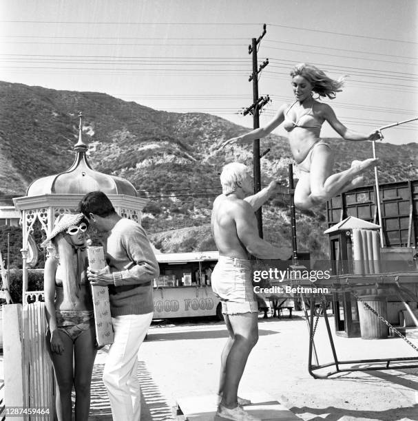 Actor Sharon Tate bounces off a trampoline into the brawny arms of David Draper, the current "Mr. America," during a beak in filming of "Don't Make...