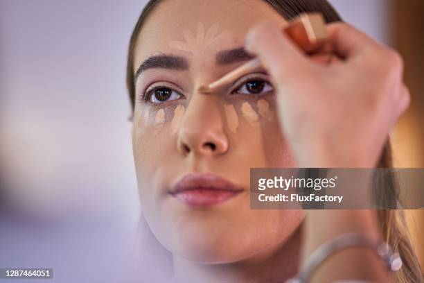 professional make up artist using a light shade of concealer on a customer to make a nose contour - concealer stock pictures, royalty-free photos & images