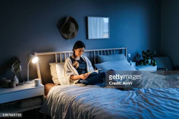 mujer leyendo un libro por la noche - reading fotografías e imágenes de stock