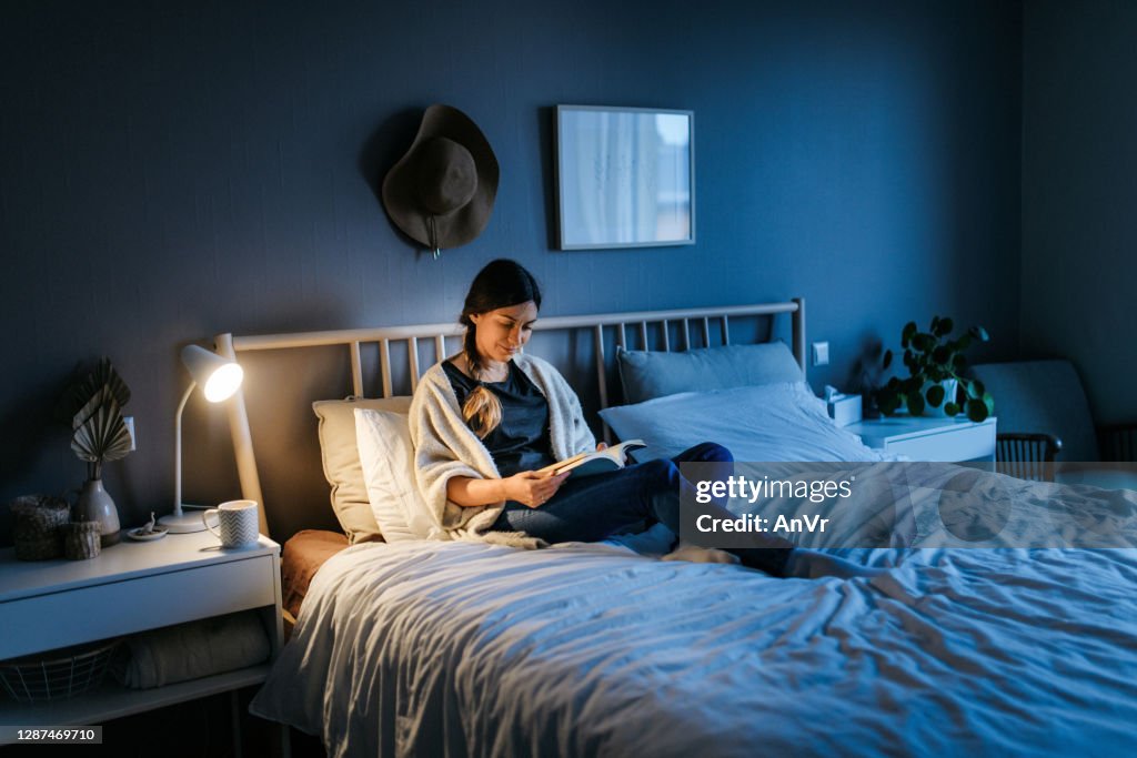 Woman reading a book at night