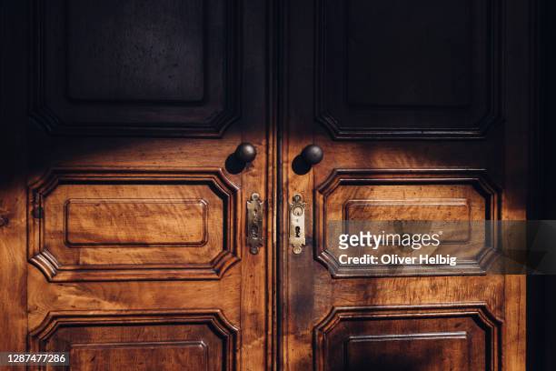 an ornately crafted wooden door in the penumbra somewhere in northern italy - big brown stock pictures, royalty-free photos & images