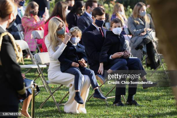 Wearing face masks to reduce the risk posed by the coronavirus pandemic, Ivanka Trump sits with her son Theodore Kushner and her husband Jared...
