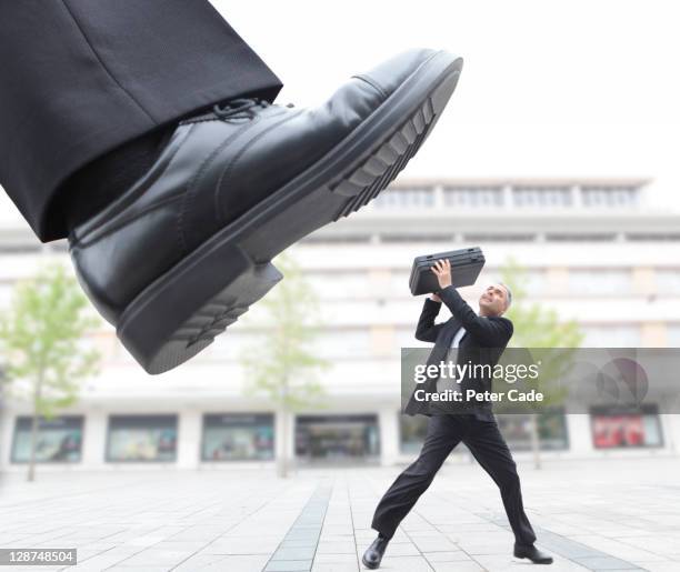 giant foot stepping on male executive - male feet imagens e fotografias de stock