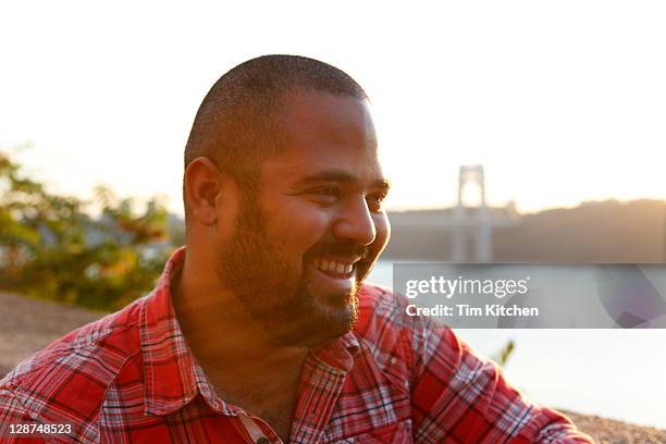 scruffy latin guy smiling near hudson river, nyc - washington heights - fotografias e filmes do acervo