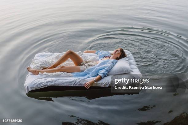 young woman swims on the lake on an inflatable mattress - materasso foto e immagini stock