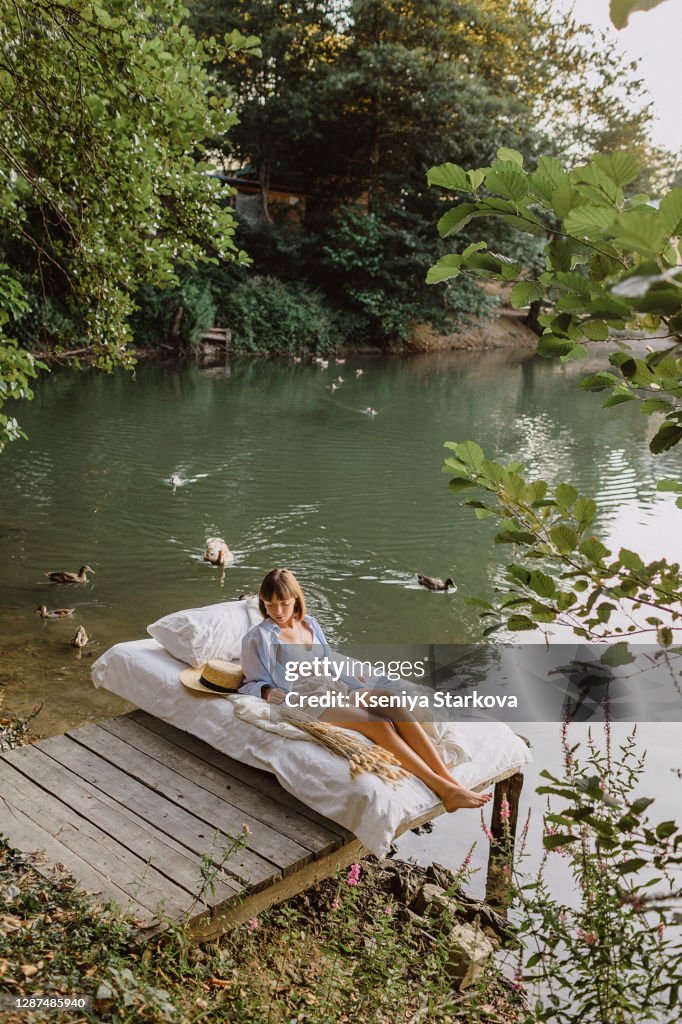 Young woman lies on an inflatable bed by the lake in the forest