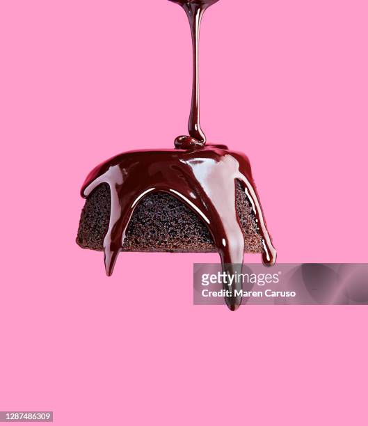 chocolate frosting being poured onto chocolate cake with pink background - indulgence foto e immagini stock