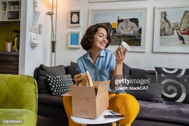 jonge vrouw pakt het pakket dat ze online besteld - blank packaging stockfoto's en -beelden