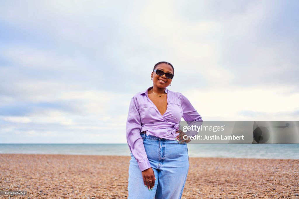 Woman standing confidently alone at the beach wearing sunglasses