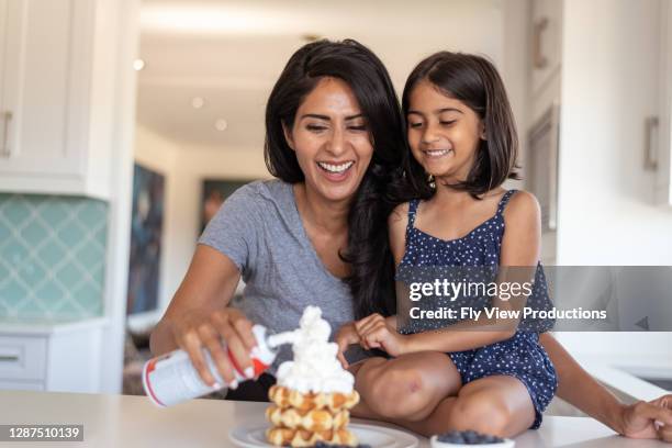 indian mother bonding with elementary age daughter while cooking together in kitchen at home - mother's day breakfast stock pictures, royalty-free photos & images