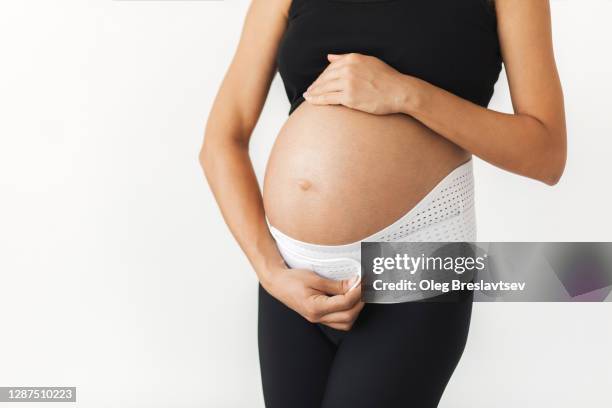 pregnant woman with naked abdomen in support bandage medical corset close-up. unrecognisable person. - orthopedic corset stock pictures, royalty-free photos & images