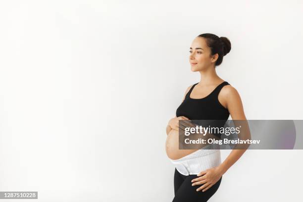 pregnant tired woman with naked abdomen in support bandage medical corset. - orthopedic corset stock pictures, royalty-free photos & images