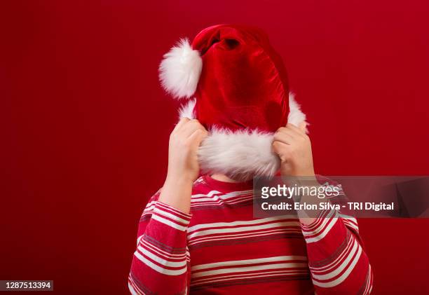 boy playing hide in santa claus hat - awkward date photos et images de collection