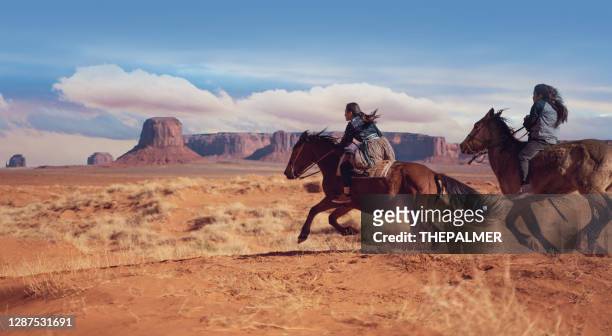 navajo siblings riding fast on horses in monument valley arizona - usa - horseback riding arizona stock pictures, royalty-free photos & images