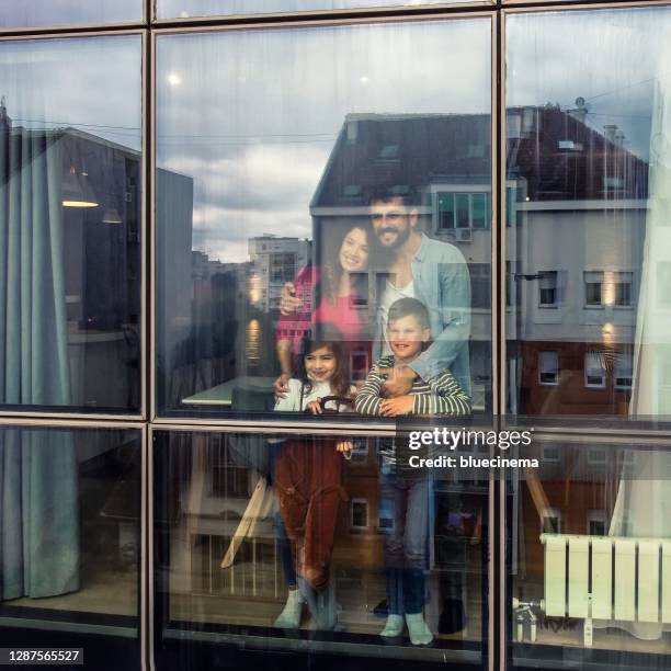 happy family at home looking through the window - bay window interior stock pictures, royalty-free photos & images