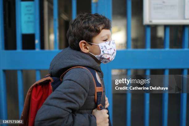 portrait of a boy wearing a protective face mask in front of school - enfant cartable photos et images de collection