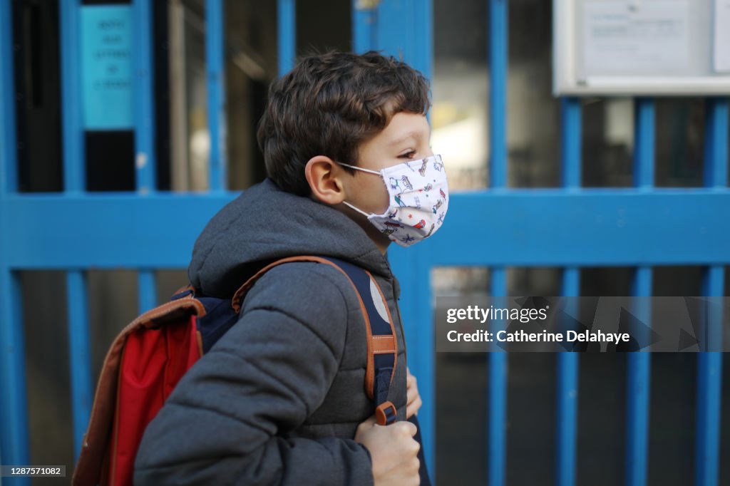 Portrait of a boy wearing a protective face mask in front of school
