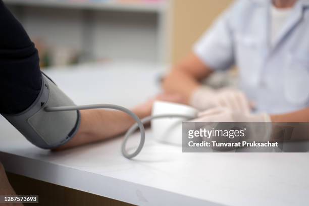 senior female doctor is checking the blood pressure of the patient. - measure foto e immagini stock