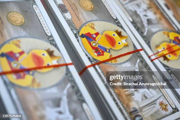 Mock Thai Baht banknotes featuring a yellow duck motif are seen during a protest outside the headquarters of the Siam Commercial Bank on November 25,...