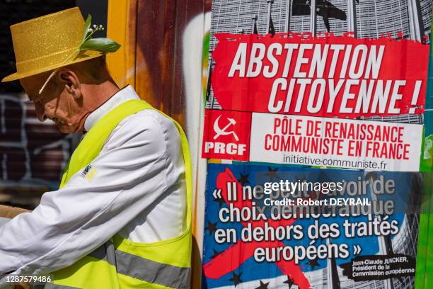 Manifestant gIlet jaune, brin de muguet et affiche communiste pour l'abstention citoyenne lors de la manifestation du 1er mai 2019 à Lyon, France.